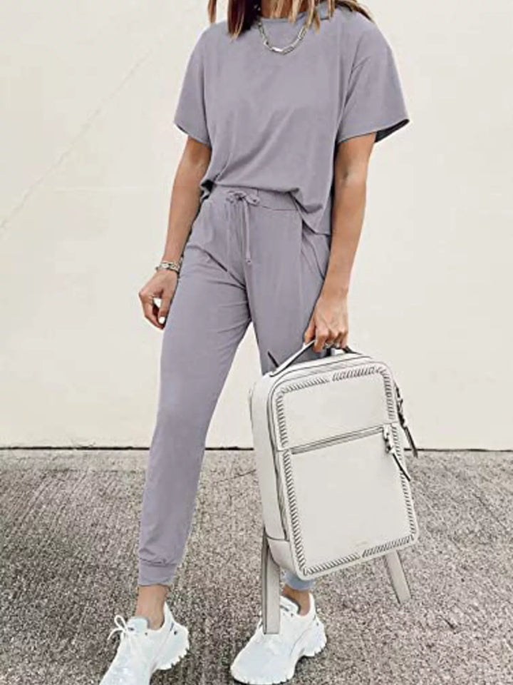 Lilac gray lounge set styled while holding a white backpack by the handle