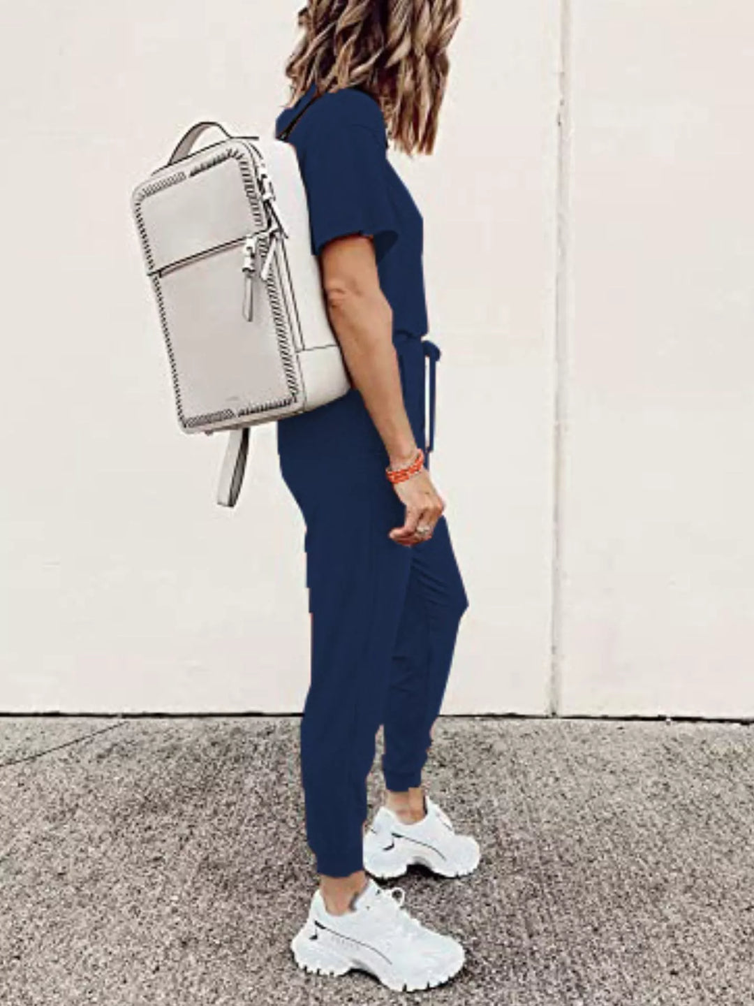 Navy tee and joggers outfit side view, white backpack and chunky sneakers