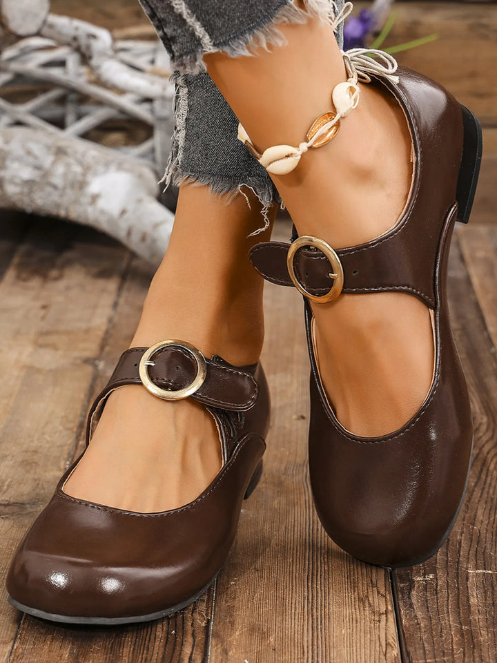 Pair of brown buckle strap shoes worn with a shell ankle bracelet