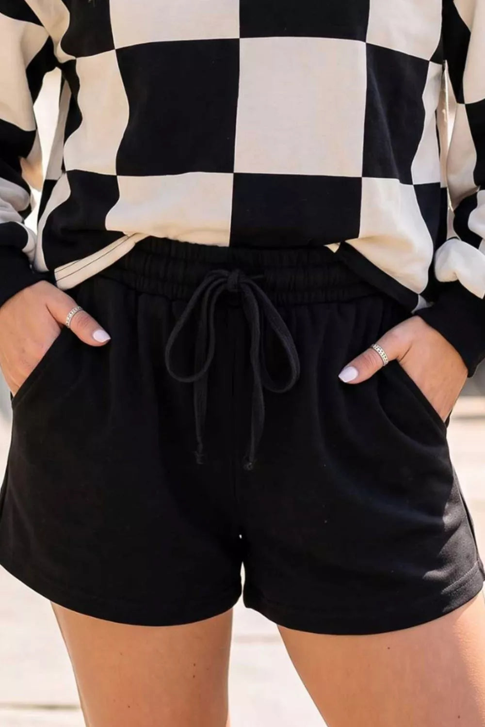 Close-up of the drawstring shorts waist and pockets beneath the checkerboard top