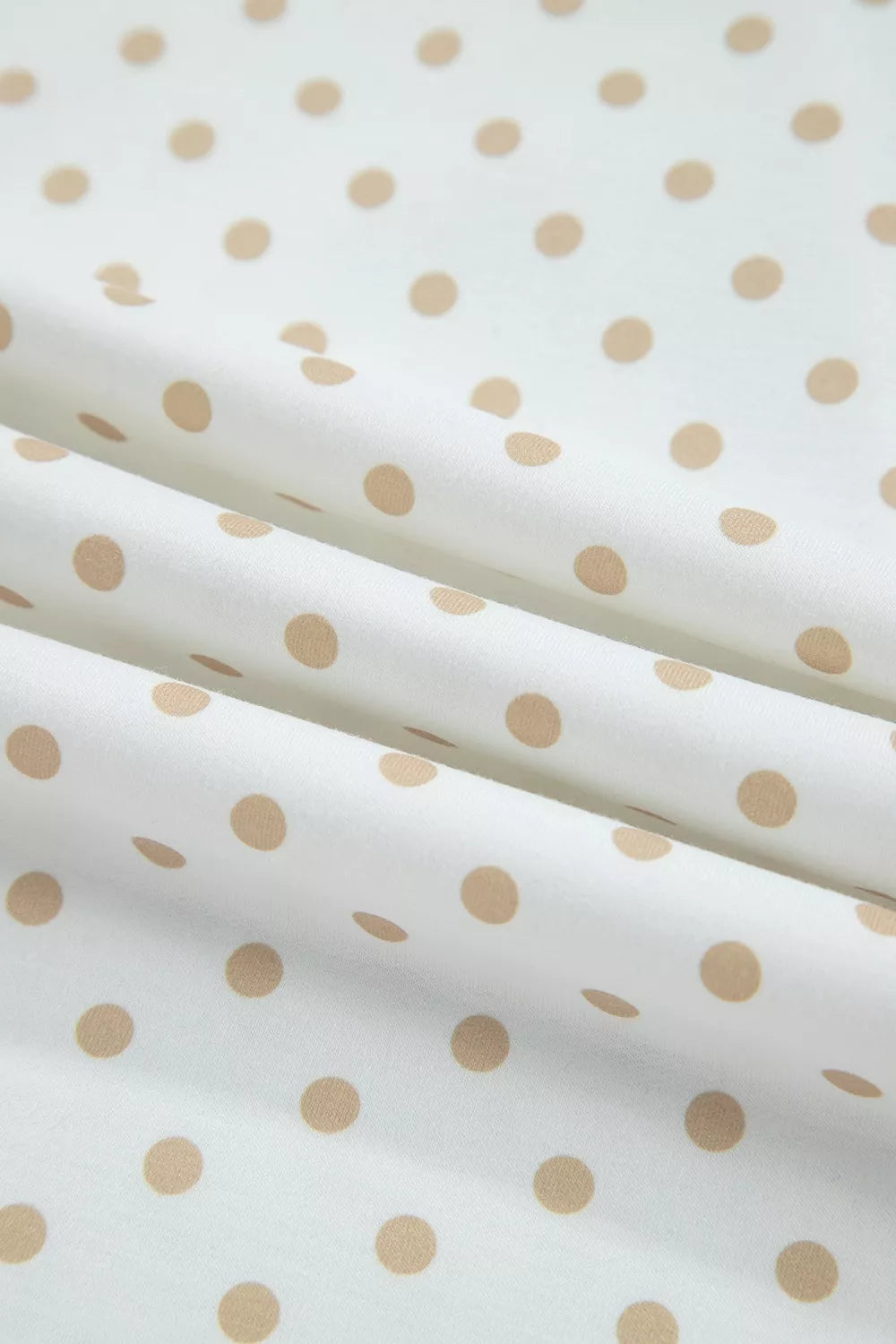 Tan polka dot pattern on white fabric, up-close texture view