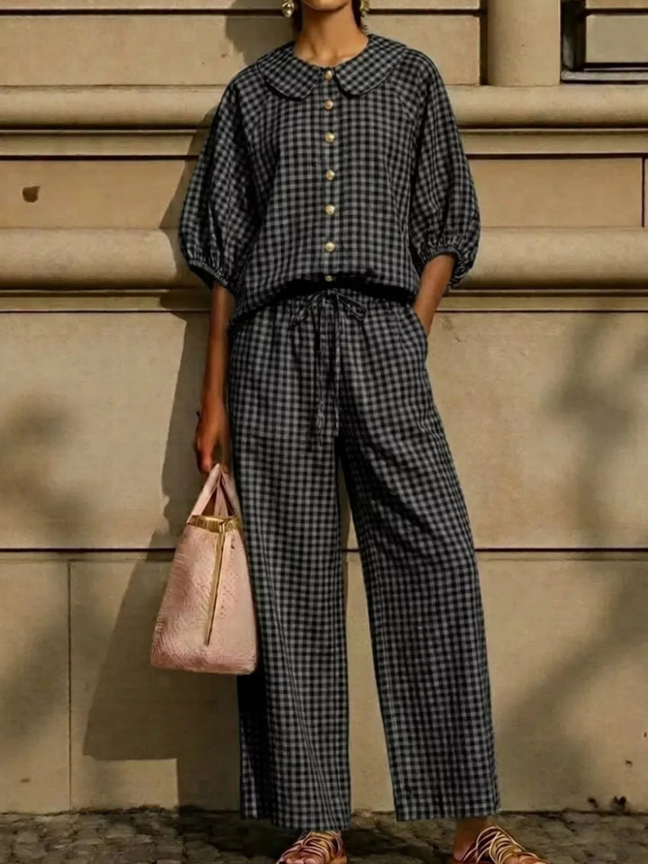 black gingham two piece set with puff sleeves standing against a stone wall