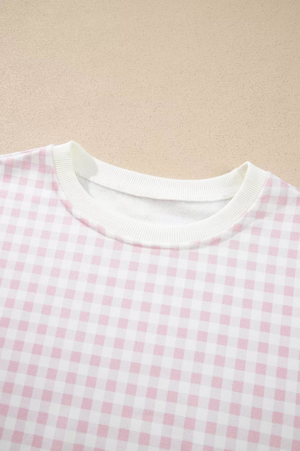 Close-up of the gingham sweatshirt round neckline with white ribbed trim