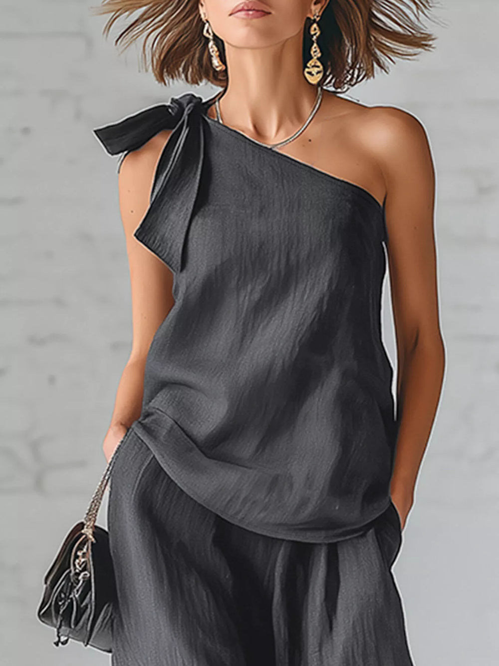 Close-up of the charcoal one shoulder top with bow detail and small handbag