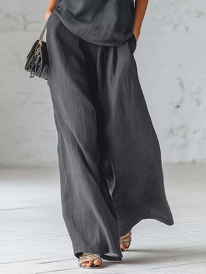 Charcoal wide leg pants walking pose with a small black bag