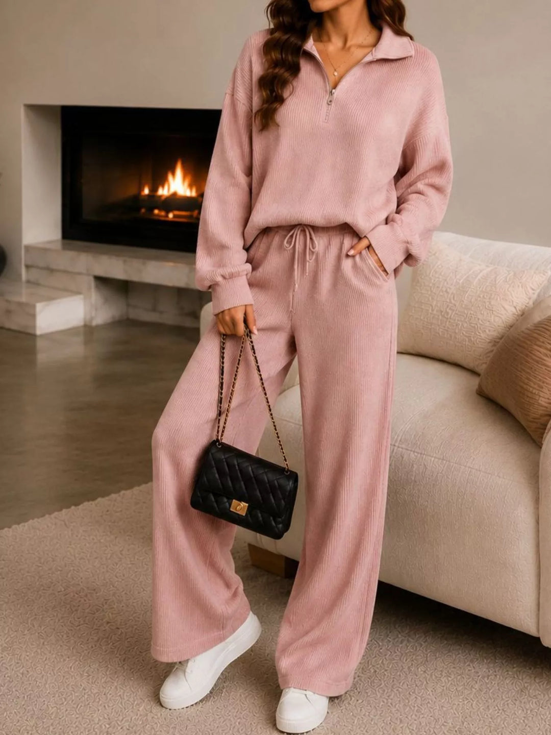 Dusty pink half zip pullover and wide leg pants, standing by a sofa