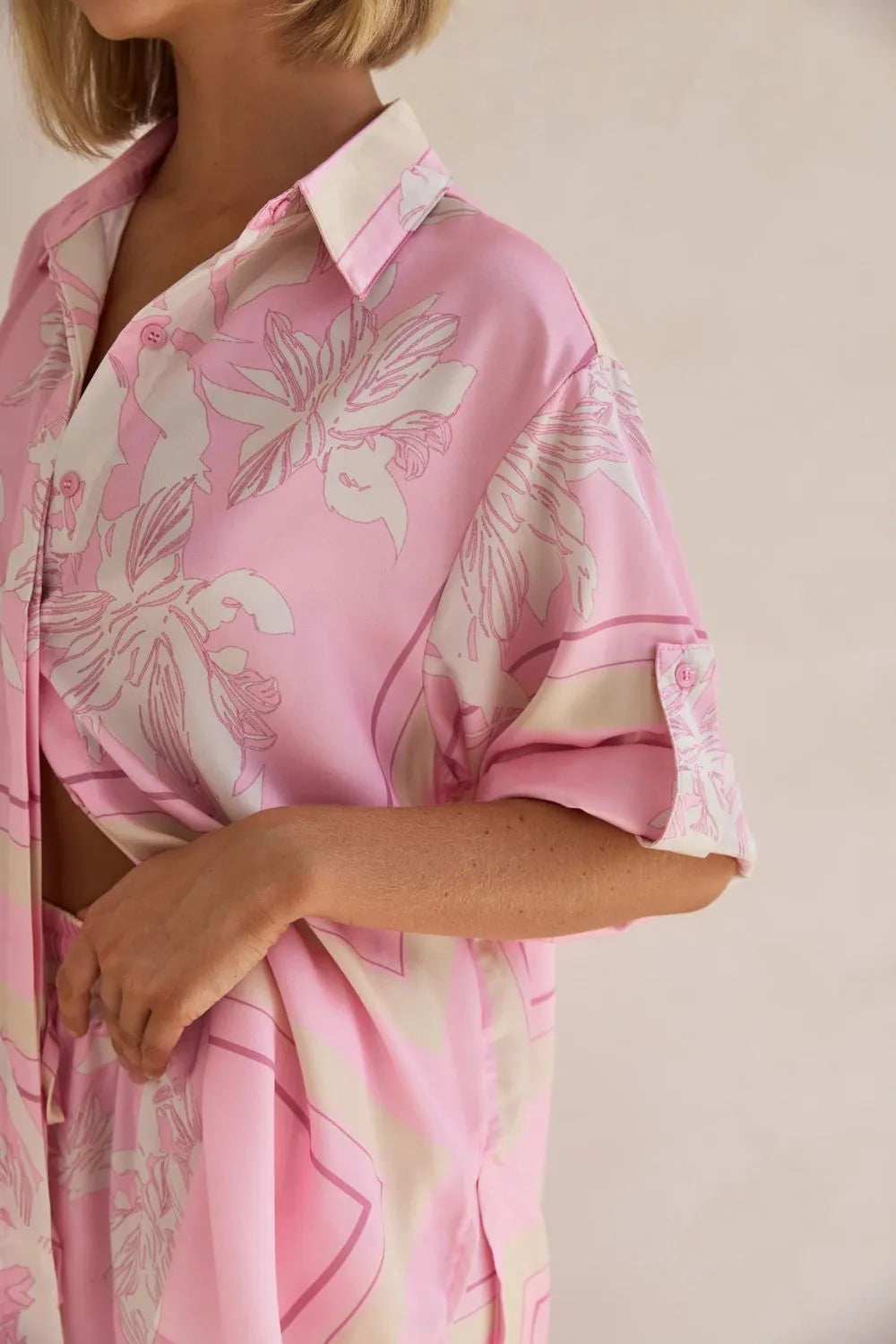 Close-up of the pink floral satin look shirt with rolled sleeves