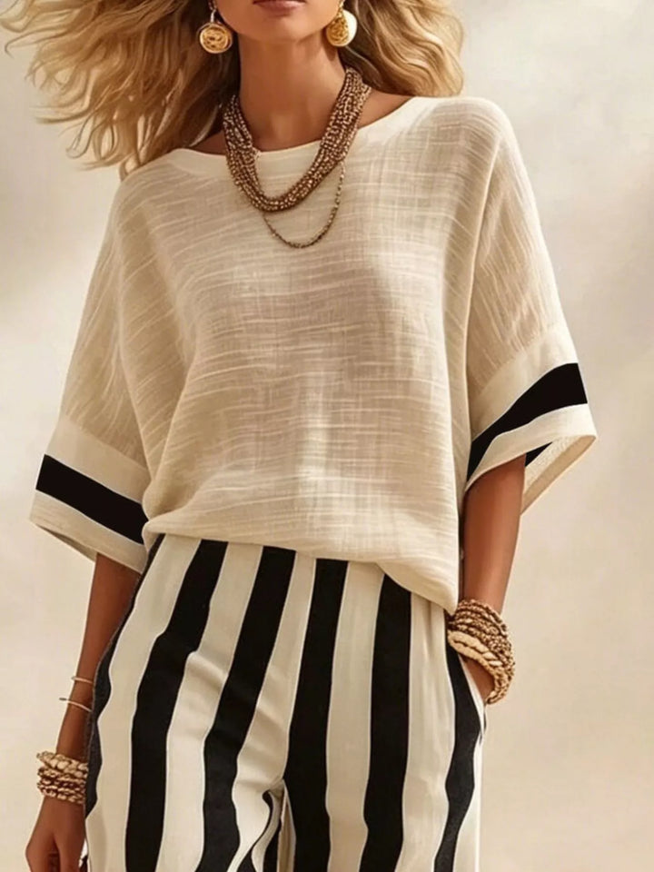 Close-up of the cream top with black sleeve trim and striped pants