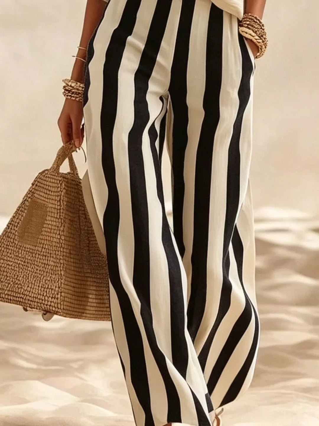 Detail of the black striped wide leg pants with a straw bag