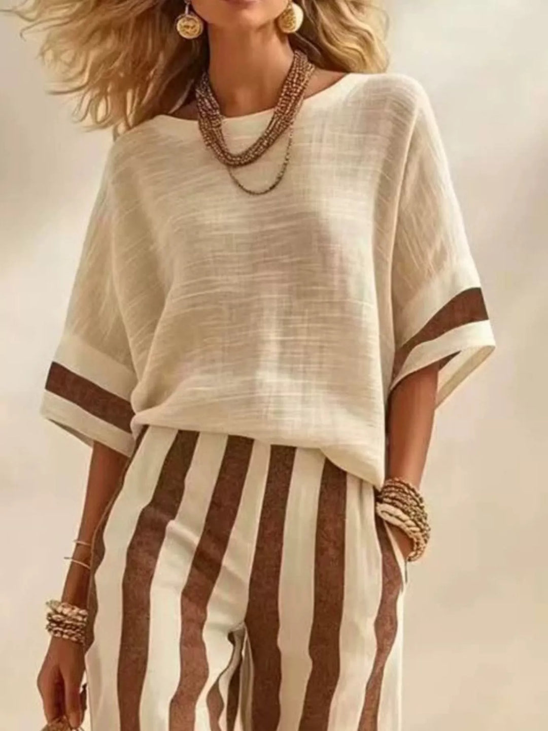 Close-up of the cream top with brown trim and brown striped pants