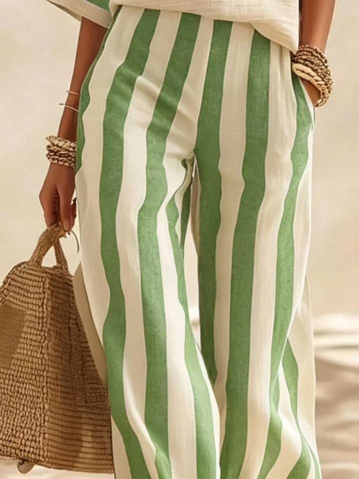 Detail of the green striped wide leg pants with a straw tote