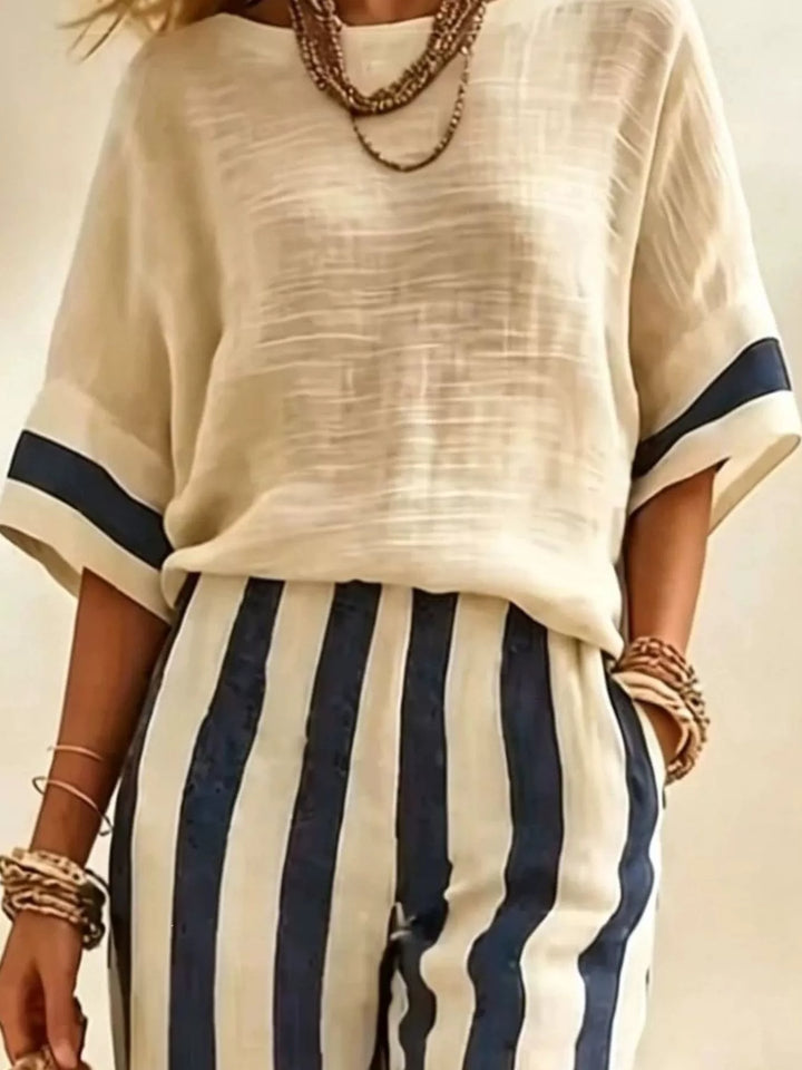 Close-up of the cream top with navy trim sleeves and striped pants