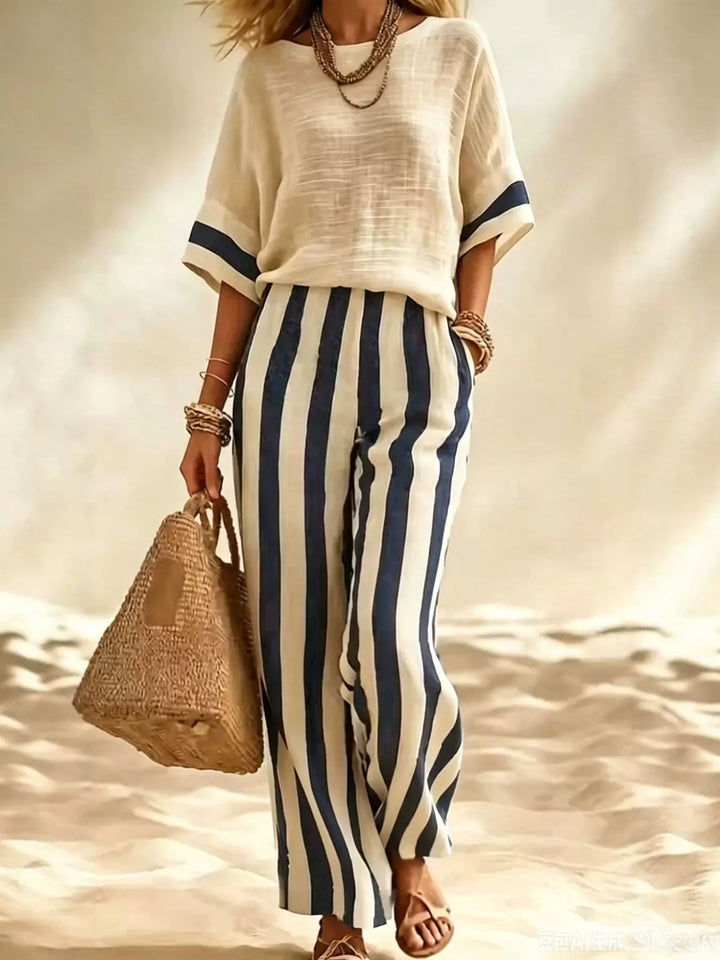 Women's matching set with navy striped wide leg pants and a cream top on a beach