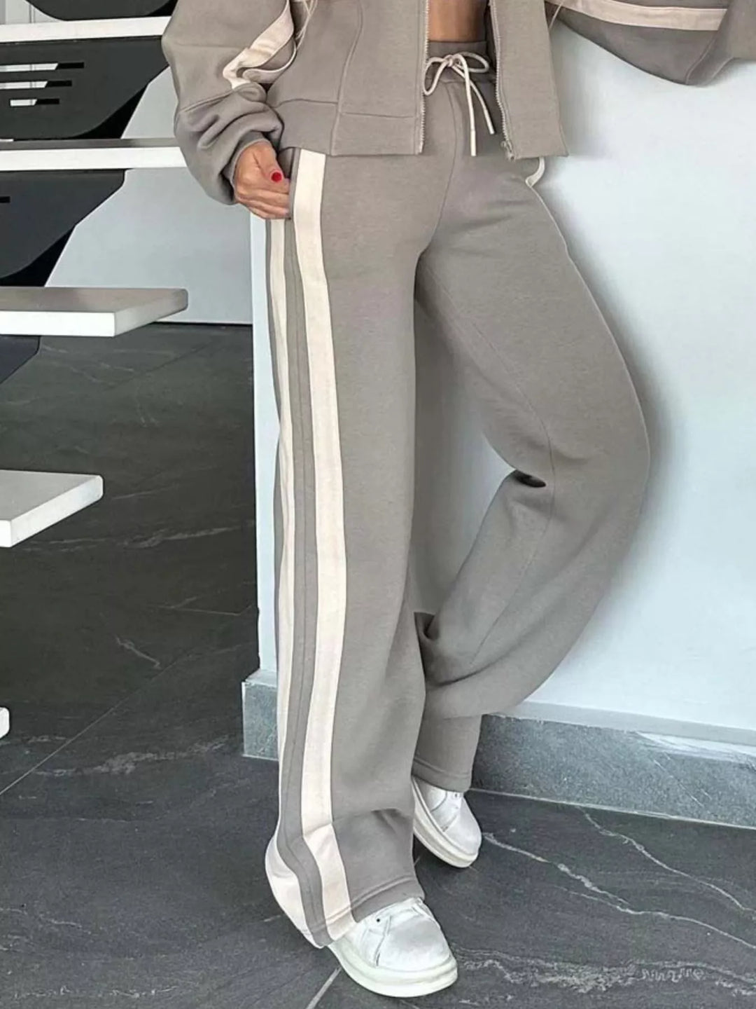 Taupe tracksuit pants with cream side stripe, lower body view with sneakers