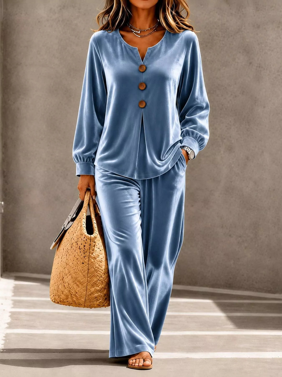 Dusty blue velvet-look top and wide leg pants set, walking with a straw tote