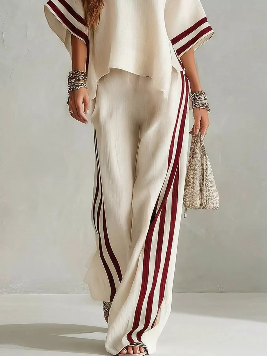 Detail of the cream top hem and striped wide leg pants with a woven bag