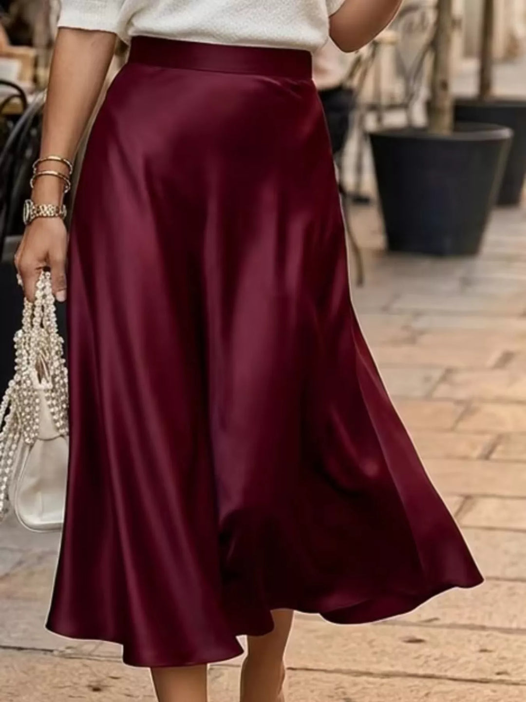 Burgundy A line midi skirt worn outdoors on a paved street, mid stride
