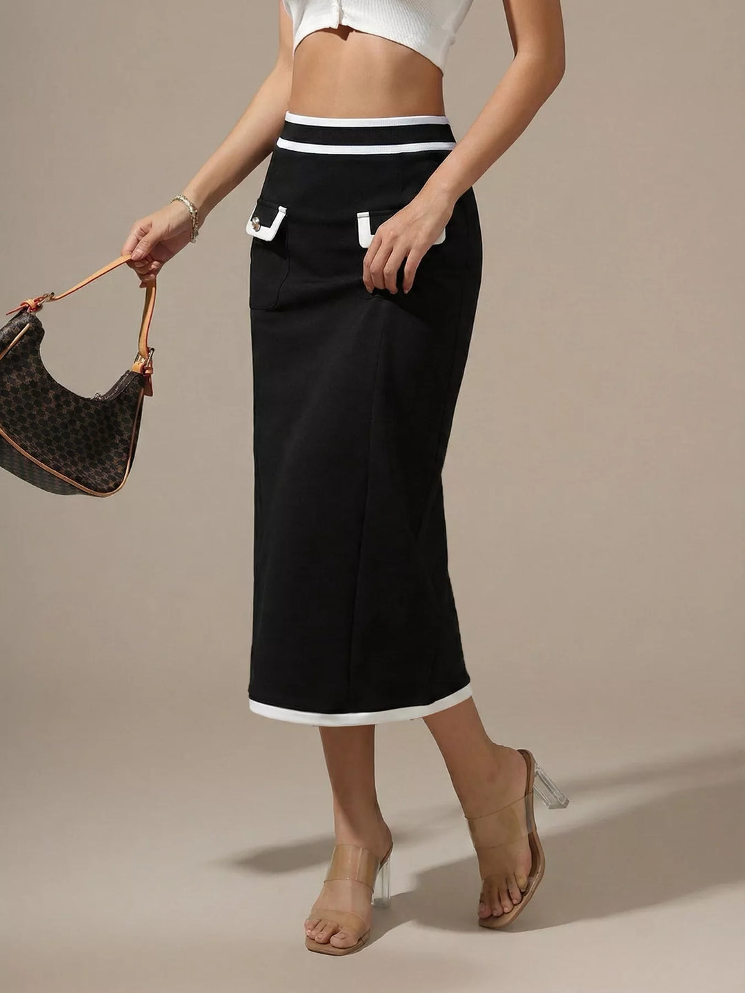 Three quarter view of the black midi skirt with contrast white hem and bag in hand