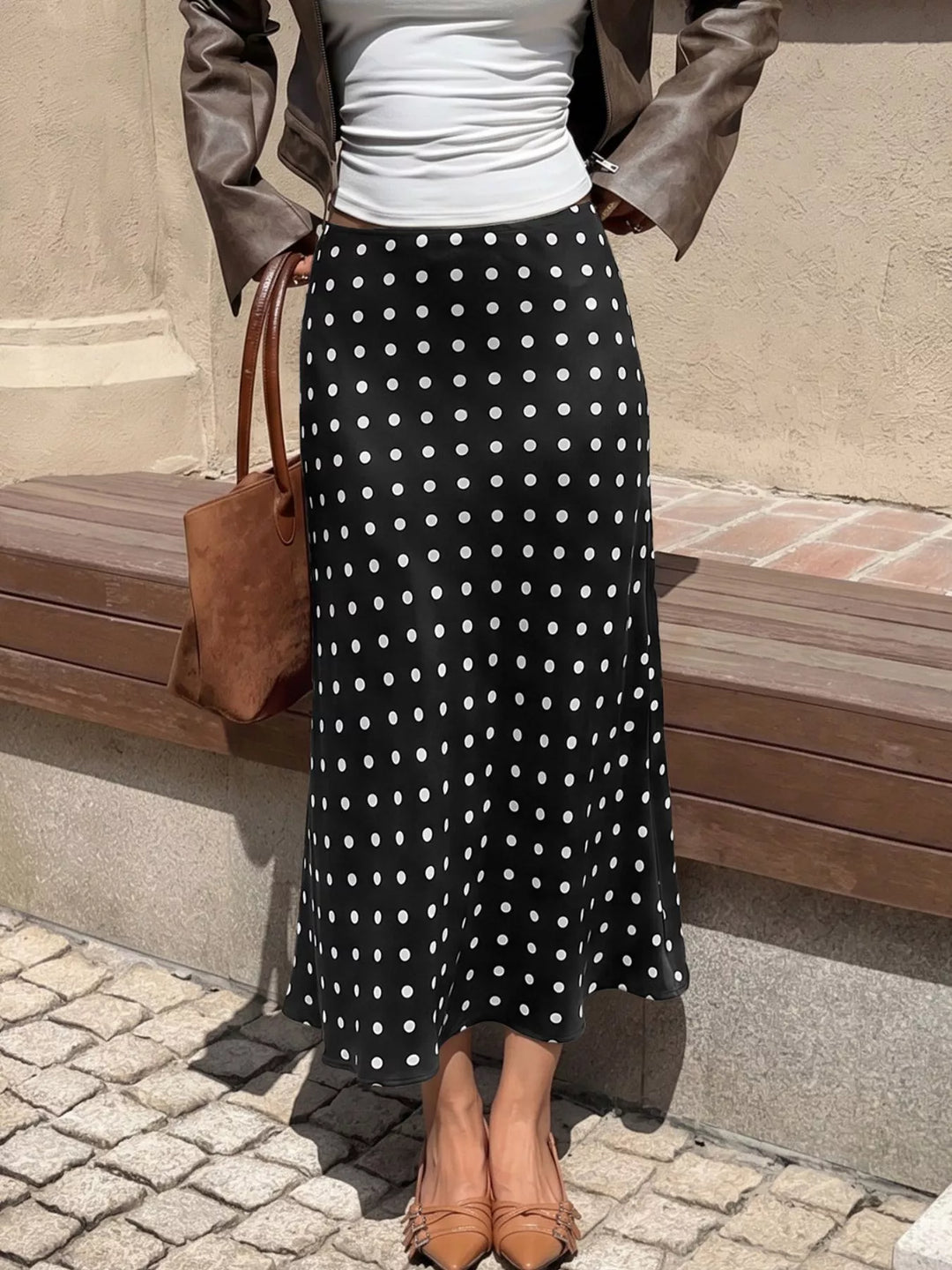 Black polka dot midi skirt styled with a leather jacket and tote bag