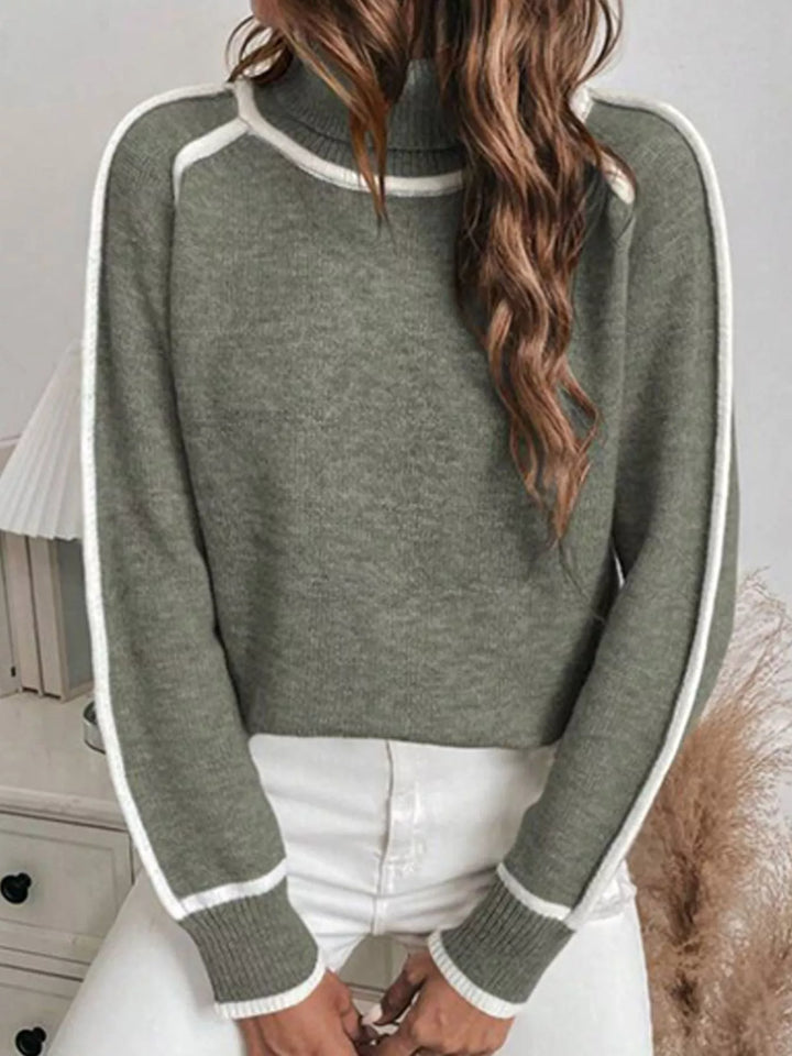 Olive mock neck sweater with contrast piping, front view with white pants