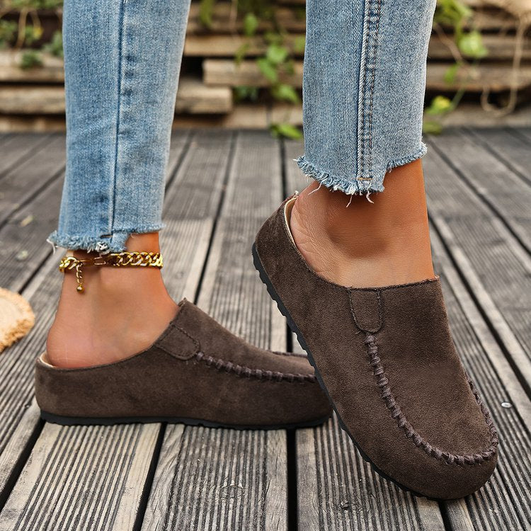 Brown backless mules worn with cuffed jeans and an ankle chain