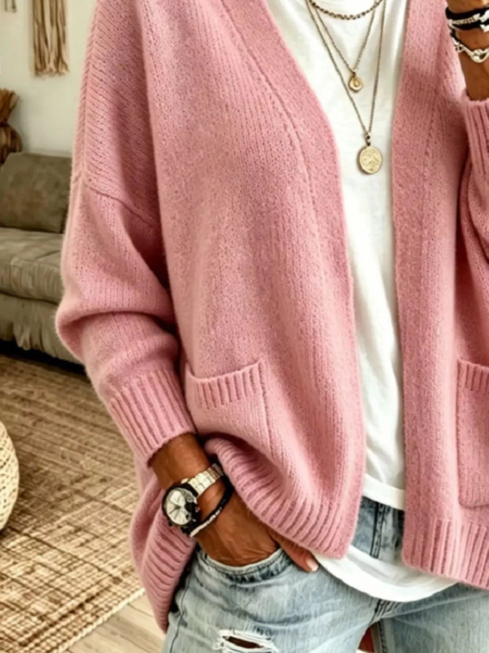 Close-up of the dusty pink cardigan pocket and ribbed hem with a hand in jeans