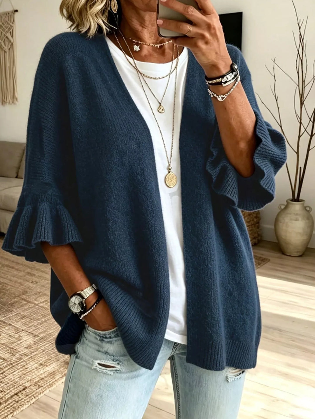 Navy open front cardigan with ruffle cuffs, hands in pockets