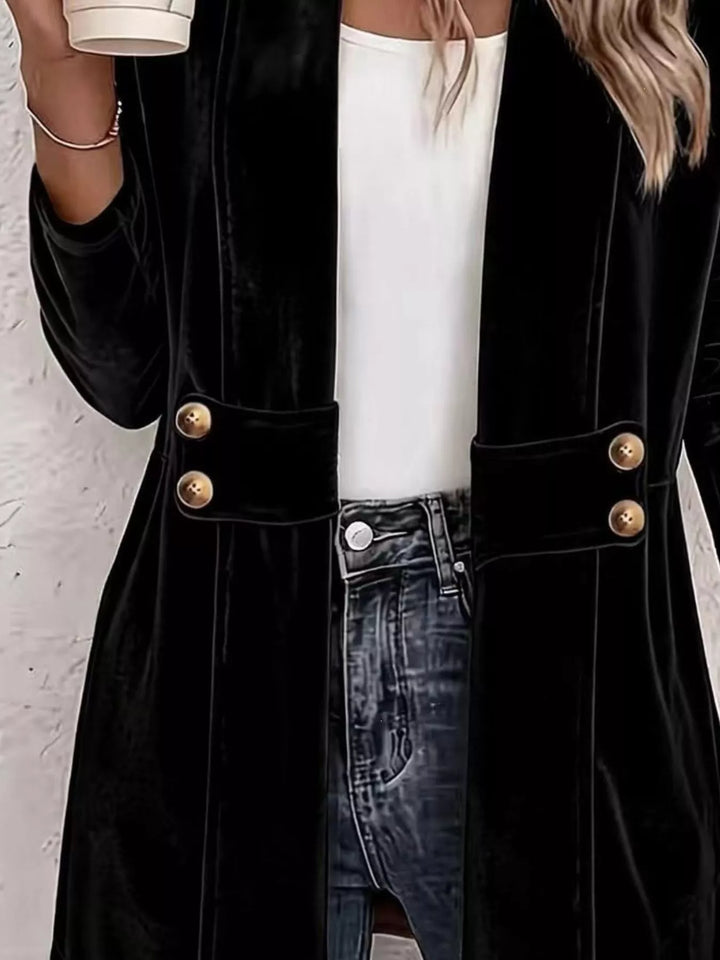 Close-up of the black cardigan belt tabs with gold buttons over a white top