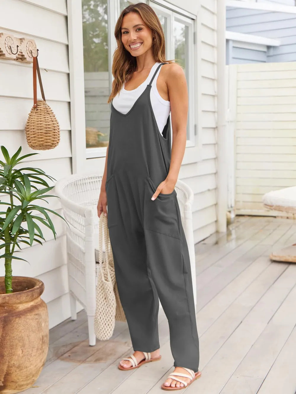Side angle of the dark gray overalls with a woven tote on the arm