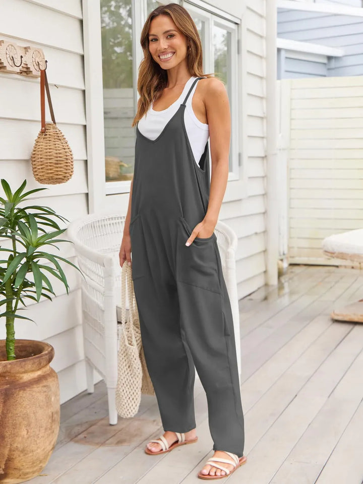 Side angle of the dark gray overalls with a woven tote on the arm
