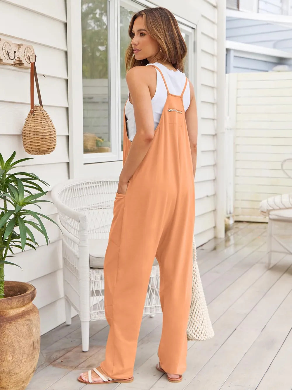 Tangerine baggy overalls in a side view with relaxed wide legs
