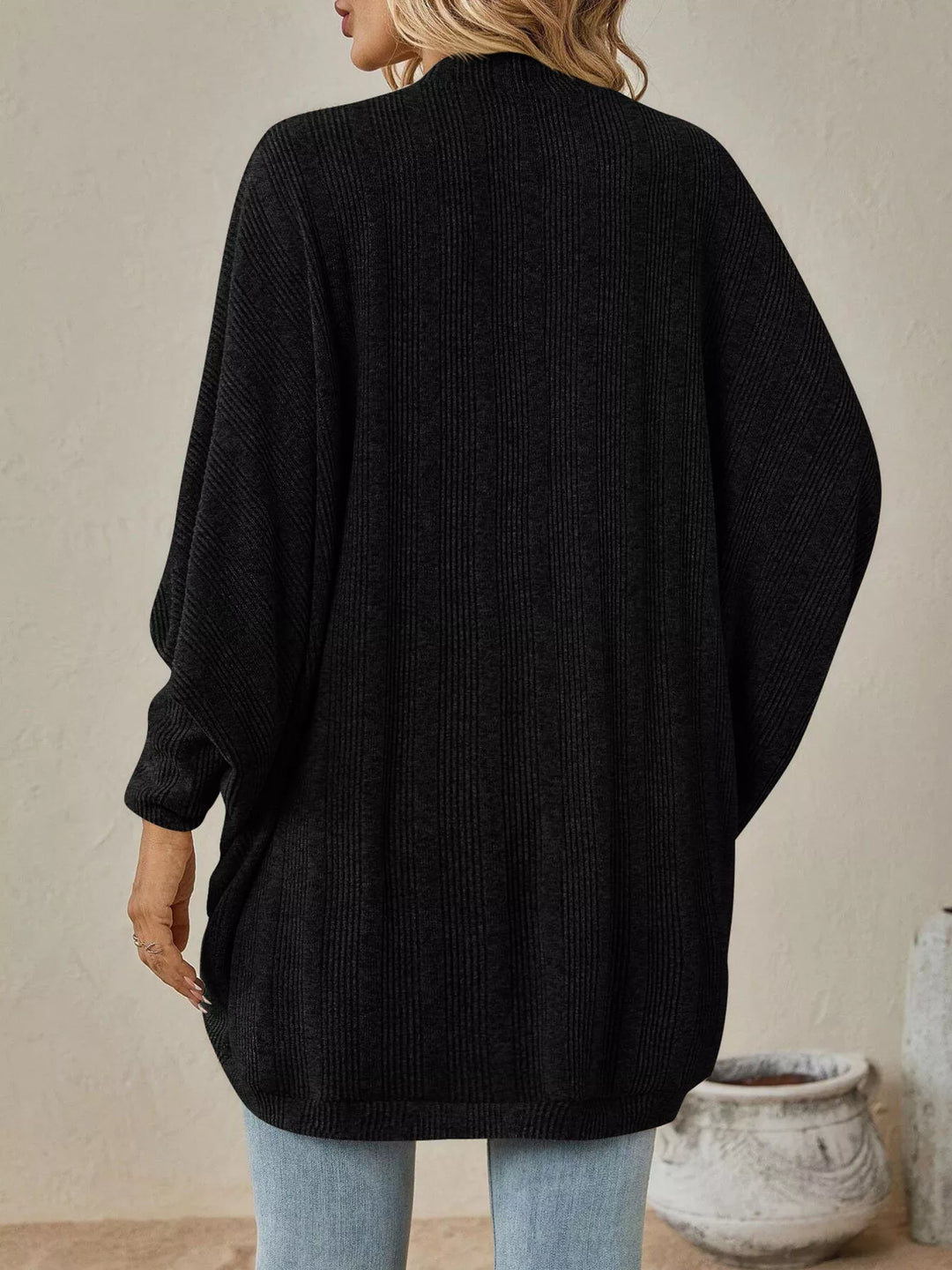 Back view of the black oversized cardigan with draped batwing sleeves