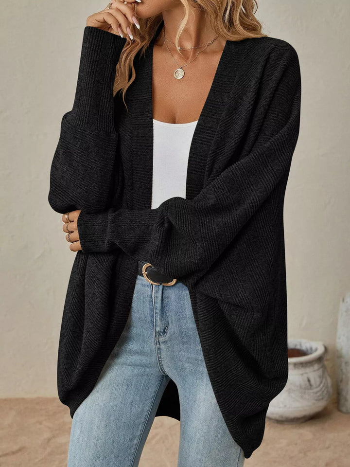 Black oversized open front cardigan with batwing sleeves, hand at chin pose
