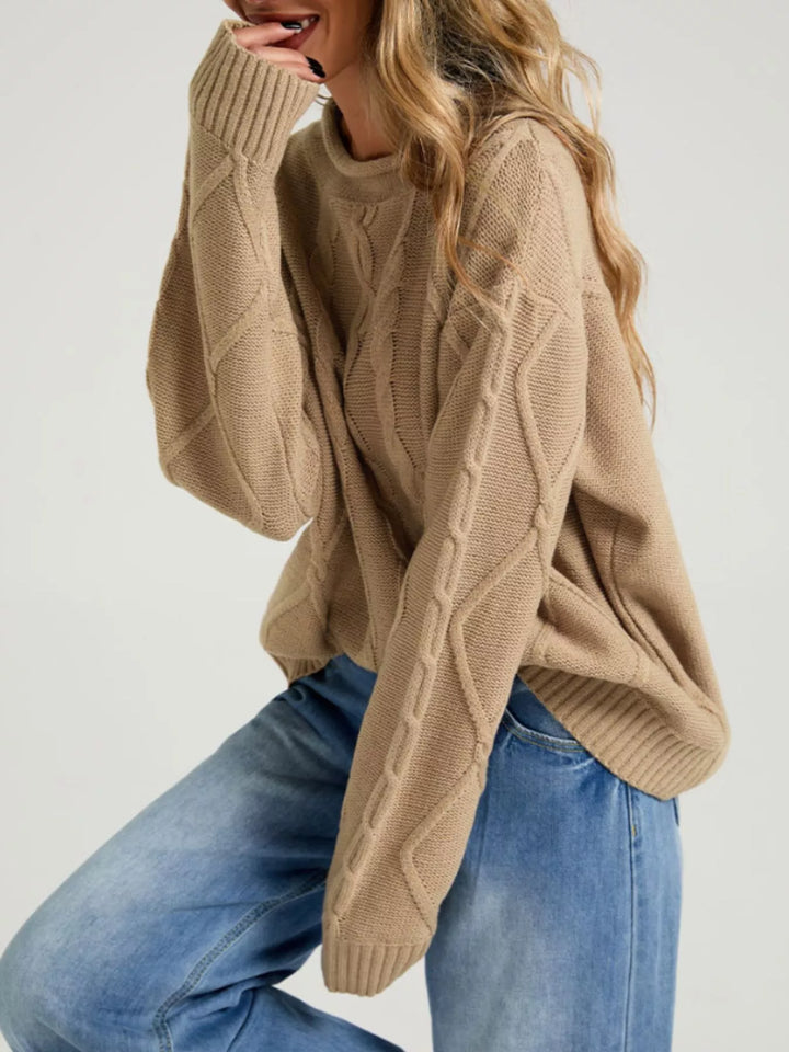 Tan oversized sweater with long sleeves, seated side pose in wide leg jeans