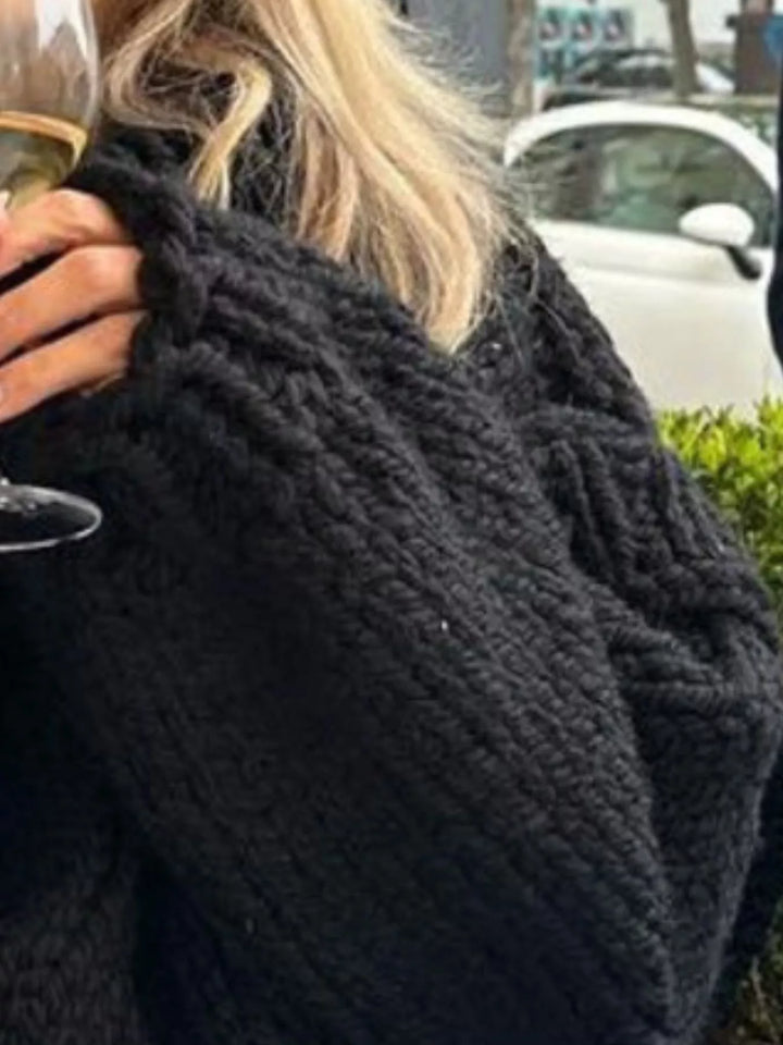 Close-up of the black chunky knit texture and layered shoulder
