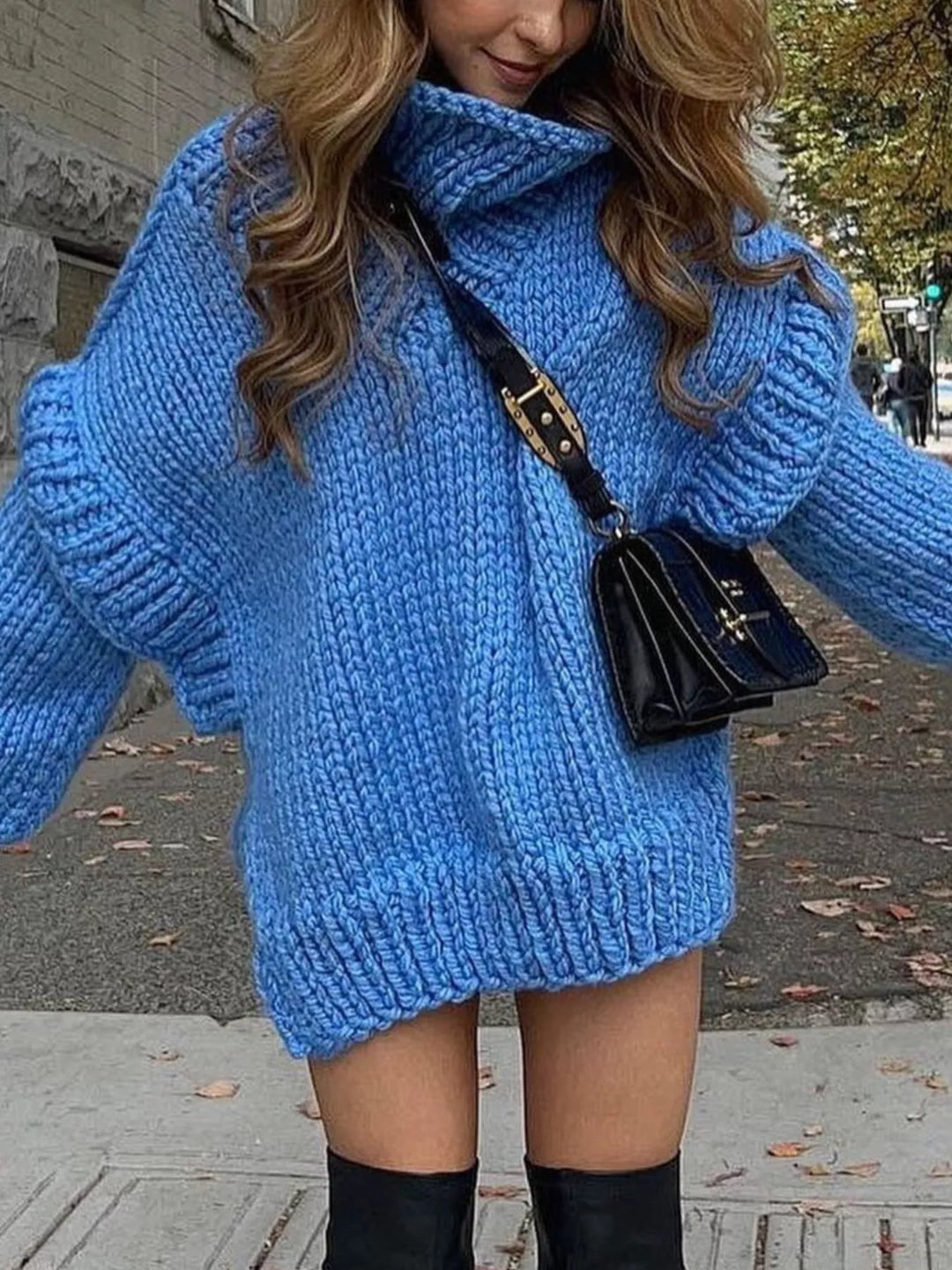 Women's oversized sweater in blue, chunky turtleneck with layered shoulders, worn with a crossbody bag