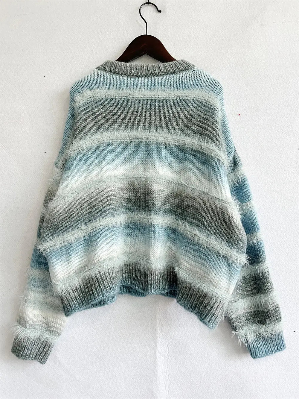 Teal blue oversized knit sweater on a hanger with sleeves spread