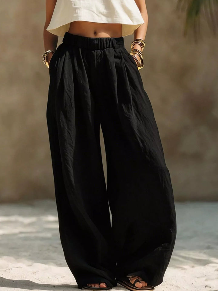 Black pleated palazzo pants with extra wide legs and a cream cropped top