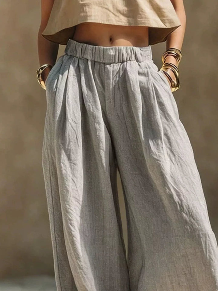 Gray palazzo pants close-up of the pleated elastic waist and hands in pockets