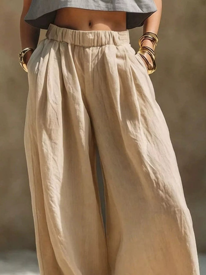 Sand pleated palazzo pants close-up with hands in the pockets