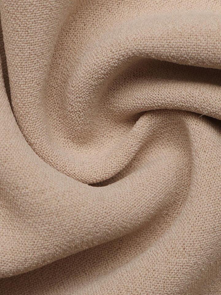 Soft draped fabric folds of the tan wide leg pants