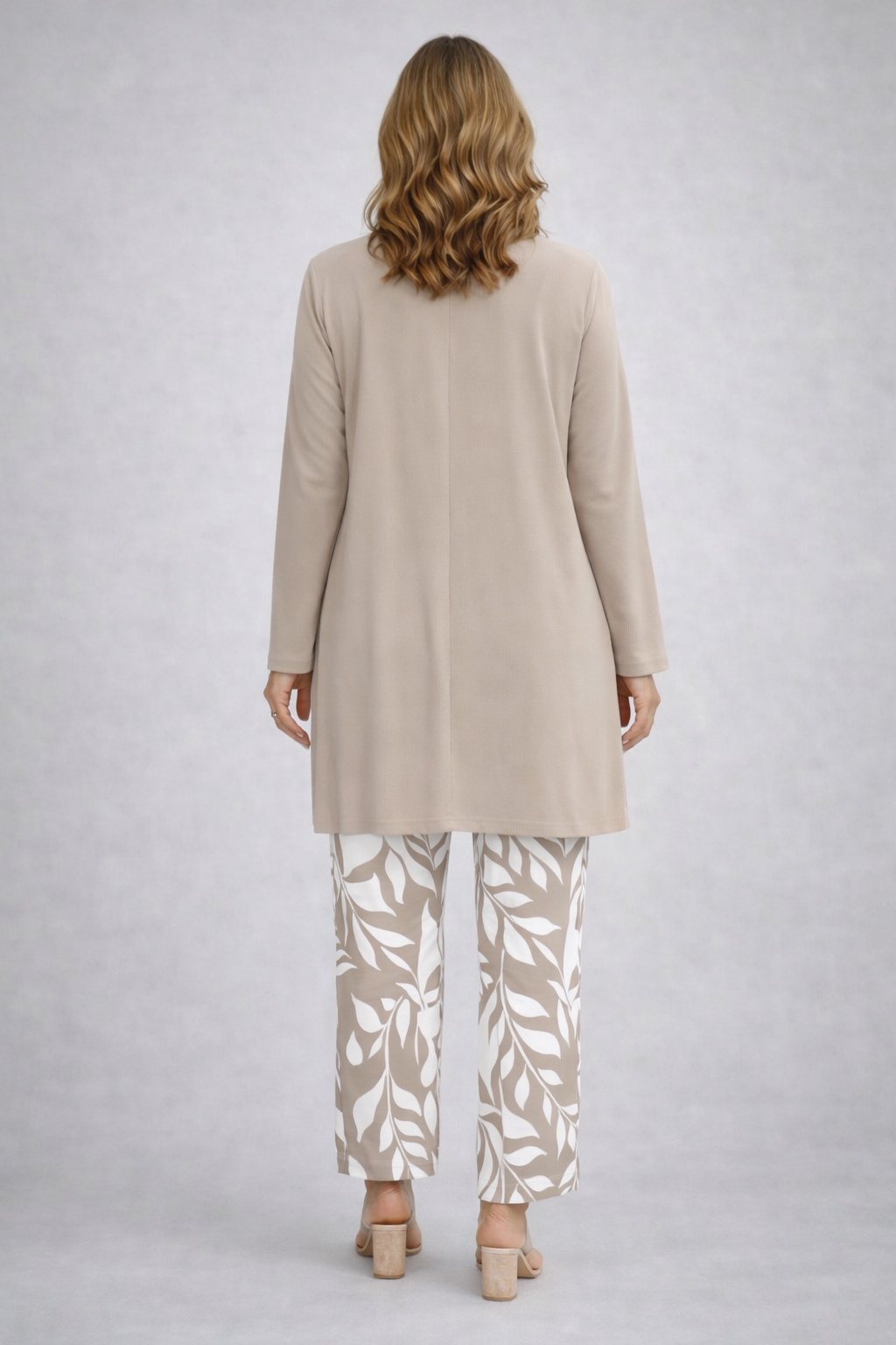 Back view of the beige cardigan with a center seam over white and beige print pants