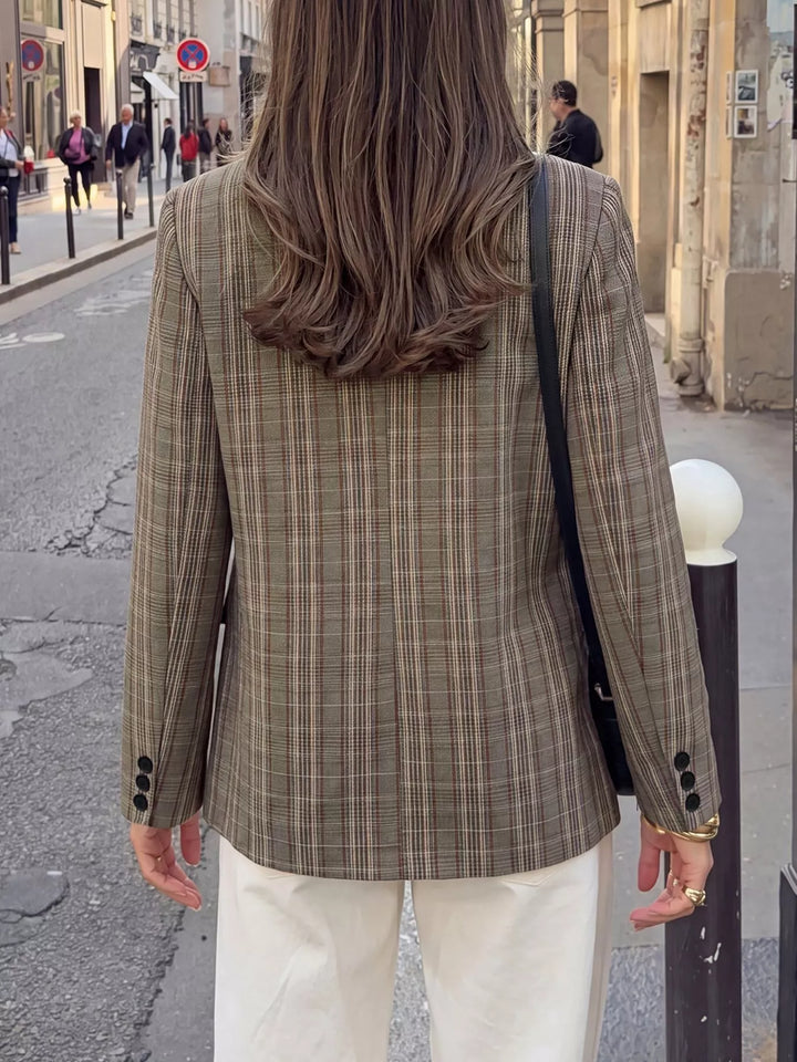 Back view of the mocha plaid blazer with a shoulder bag strap, street setting