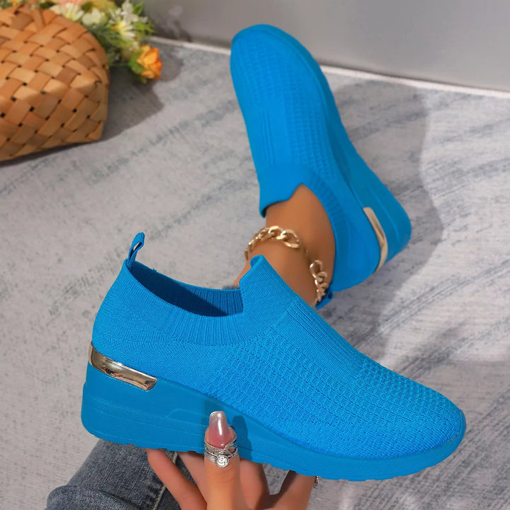 Bright blue knit platform sneakers held on the foot, top angle