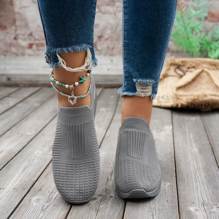 Gray slip on platform sneakers shown from the front with frayed jeans