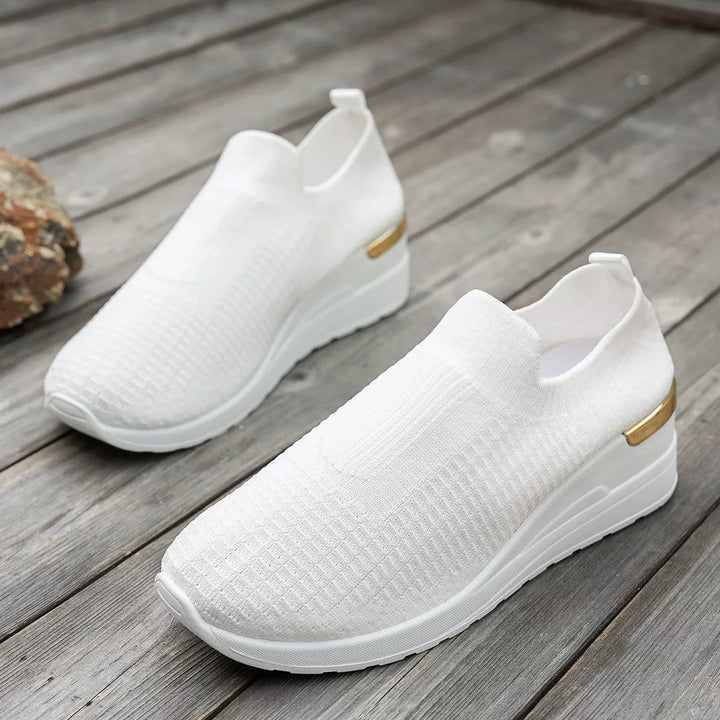 White knit platform sneakers resting on a wooden floor, pair view
