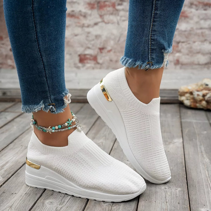 White slip on platform sneakers with hidden wedge, side view with jeans