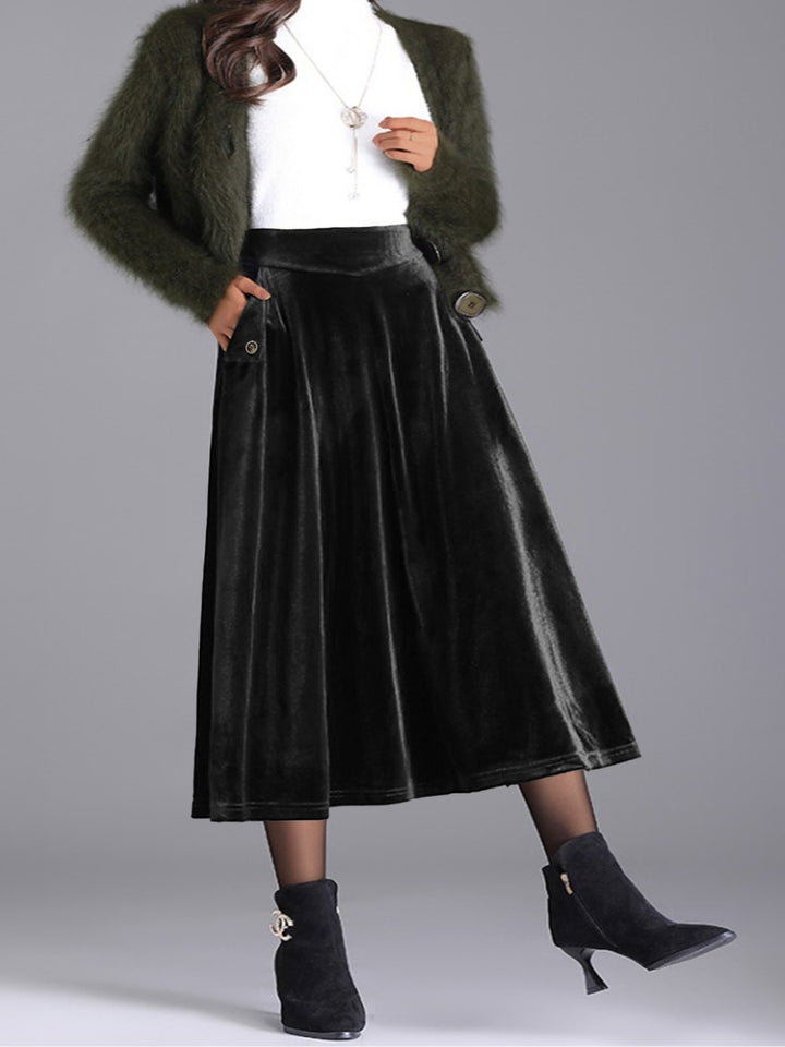 Black velvet-look midi skirt styled with a white top, green fuzzy cardigan and boots
