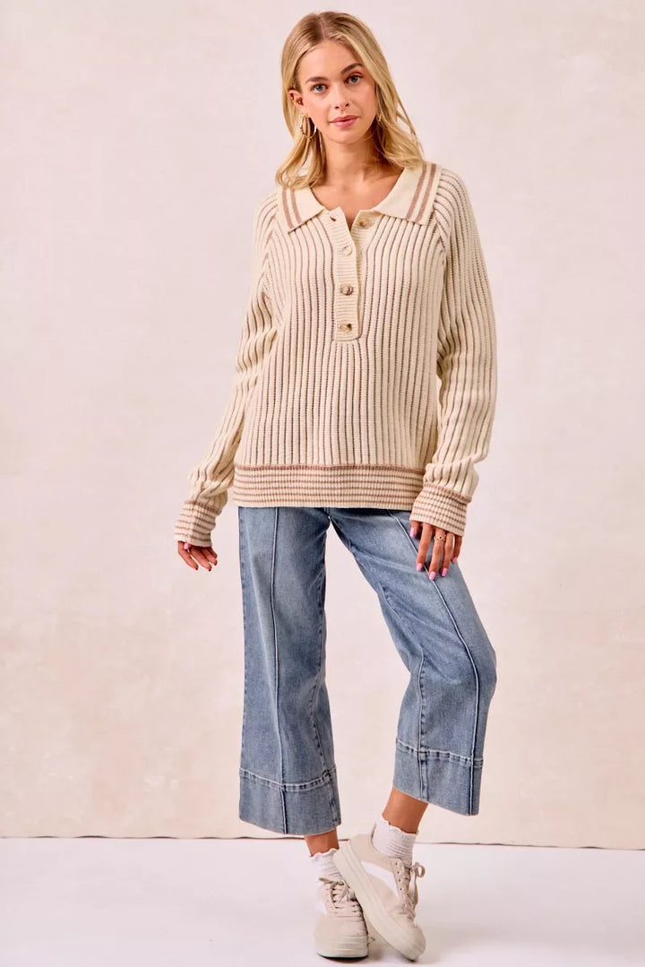 Cream ribbed polo sweater styled with cropped jeans and white sneakers, standing