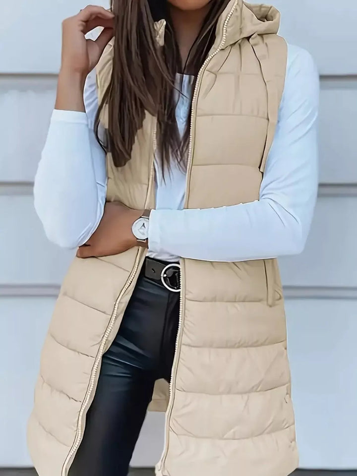 Beige longline quilted puffer vest with hood, open zip, worn with black leather pants